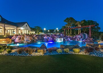 Synthetic grass lawn next to a large backyard swimming pool