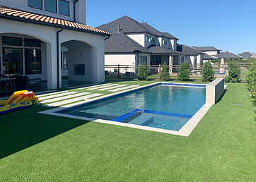 Backyard swimming pool area with artificial grass lawn