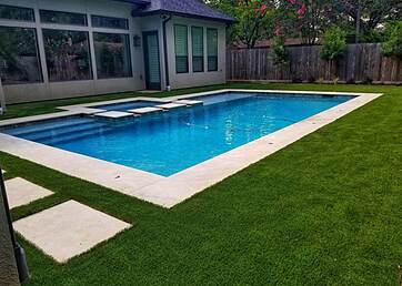 Artificial grass lawn in the backyard next to a in ground pool