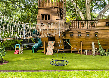 Backyard pirate ship playground with artificial grass lawn surrounding it