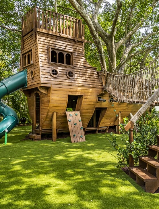 Backyard wooden playhouse shaped like a boat with Turf Fiber